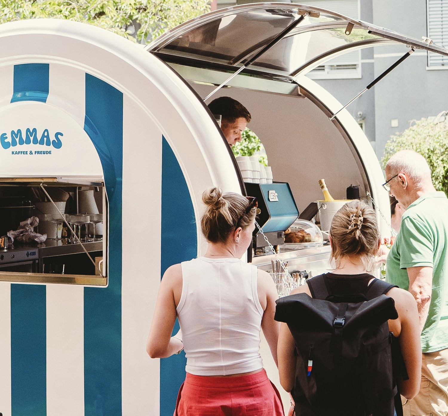 Nahaufnahme von Gästen an der Theke von Emmas blau-weißem Kaffeewagen
